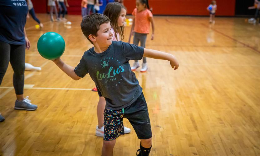 A boy with brown hair prepares to throw a ball in PE class